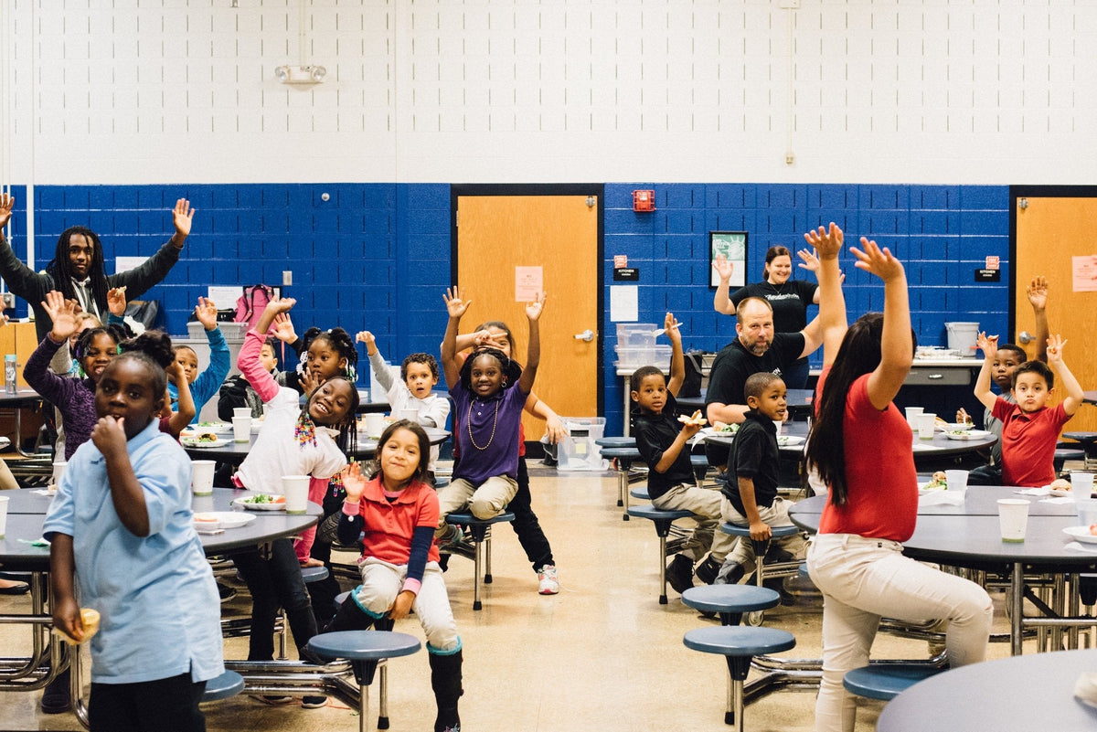 kids with hands up in school cafeteria
