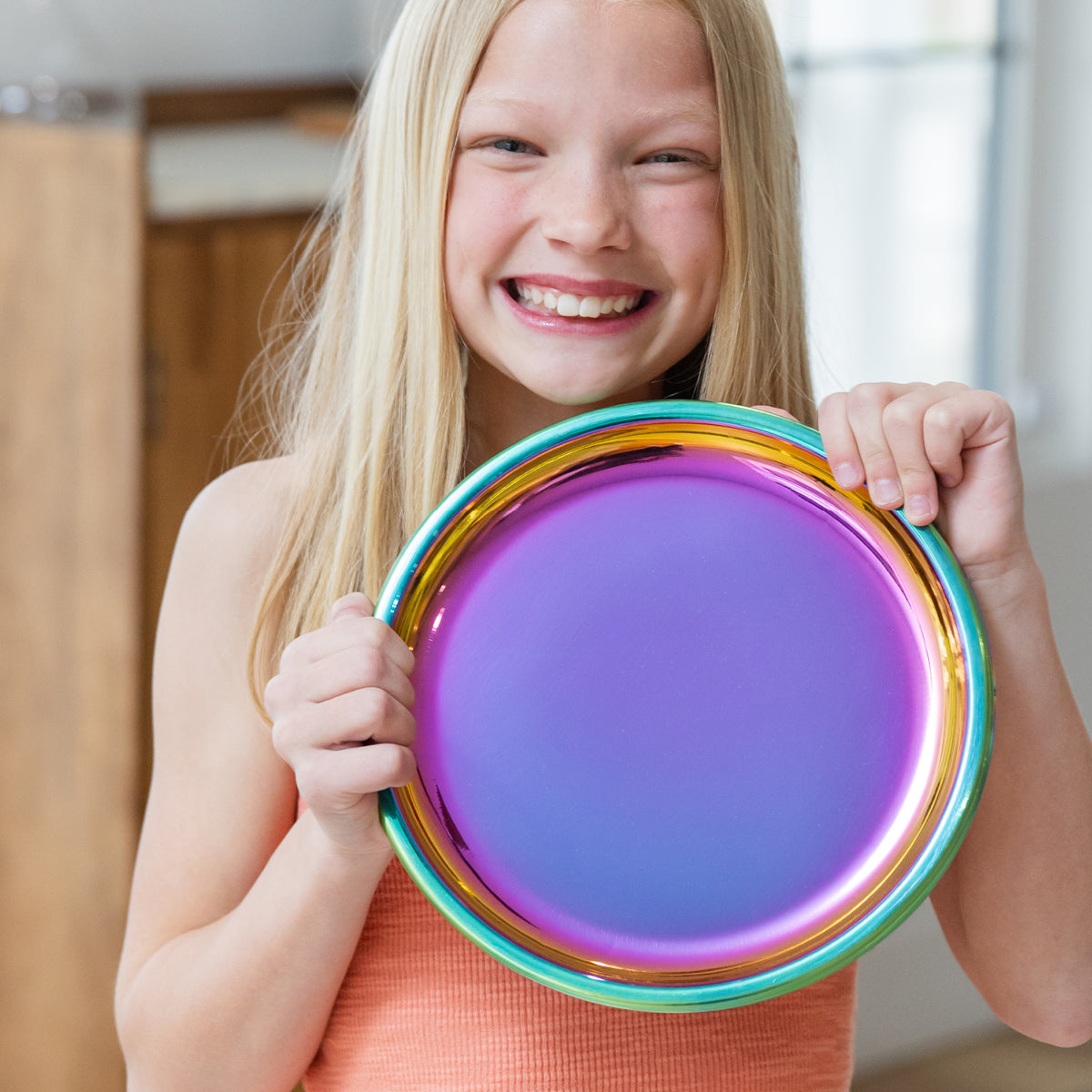 Young girl holding a colorful rainbow stainless steel plate.