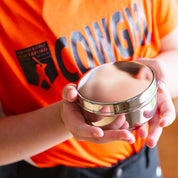 Person holding a stainless steel food container with an orange shirt