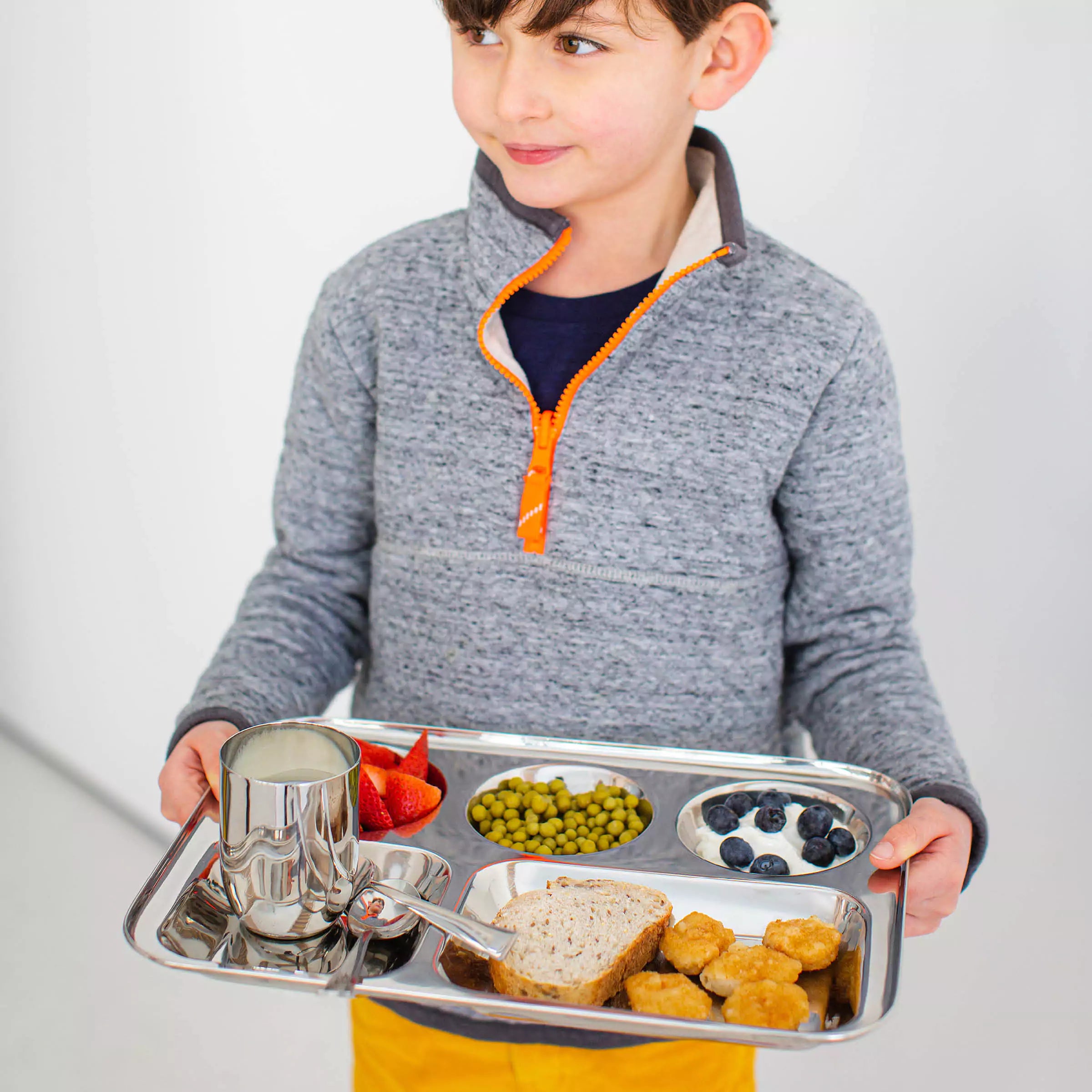 Little boy holding divided stainless steel tray with 8 ounce cup, fork, and spoon. stainless steel trays for kids