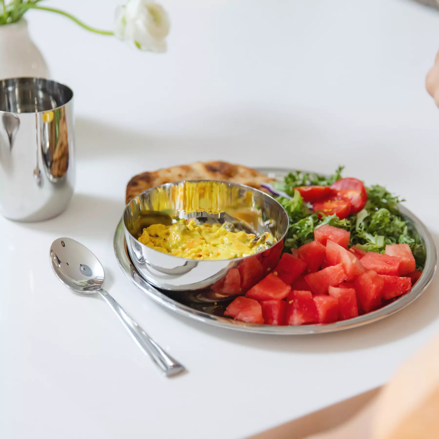 Plated dish with watermelon, salad, and a bowl of yellow food on a white table - all in Ahimsa's Purposeful Portions Set.