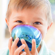 Child holding a reflective blue stainless steel bowl