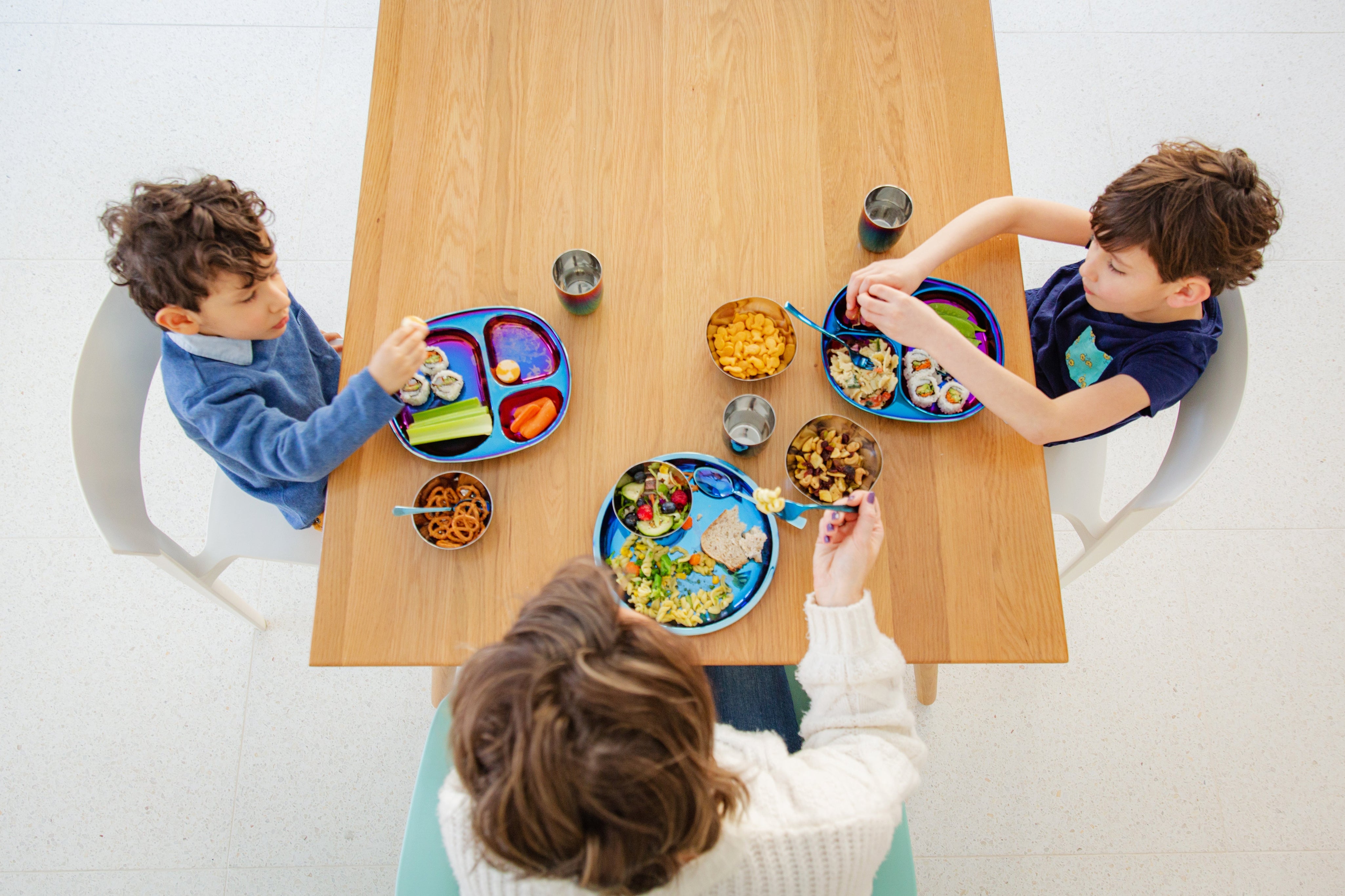 kids sitting at table eating a meal with stainless steel dishes