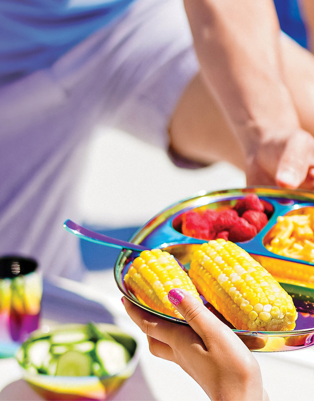 Balanced Bites stainles steel divided compartment plate with corn, raspberries, and pasta at a backyard barbeque. The perfect plates for poolside, outdoors, or indoors.