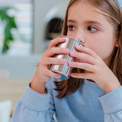 10 year old girl drinking out of a 10 ounce stainless steel cup with a rolled edge