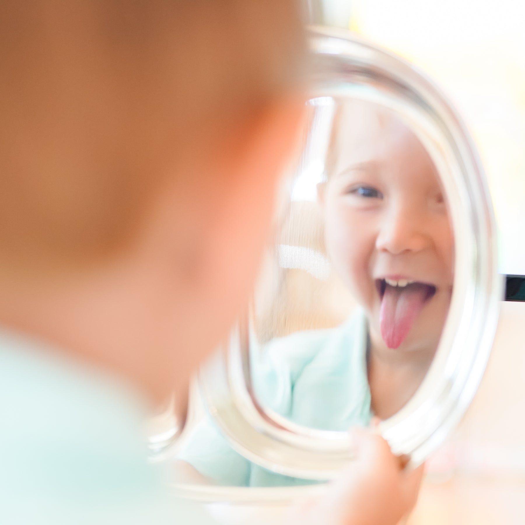 4 year old child making a silly face seeing his reflection in a classic or silver, reflective divided plate. Stainless steel dishes for toddlers, kids, and adults