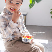 Child holding a bowl of snacks with 'Essentials Bowl 8 oz' text eating peppers / enjoying a healthy snack with a dishwasher safe, cute, durable bowl.