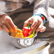 Child putting vegetables in an 8 ounce stainless steel bowl with reflective sides, the cutest little bowl that also does not leach harmful chemicals into children's foods since it is made of stainless steel, a non-porous material recommended by pediatricians.