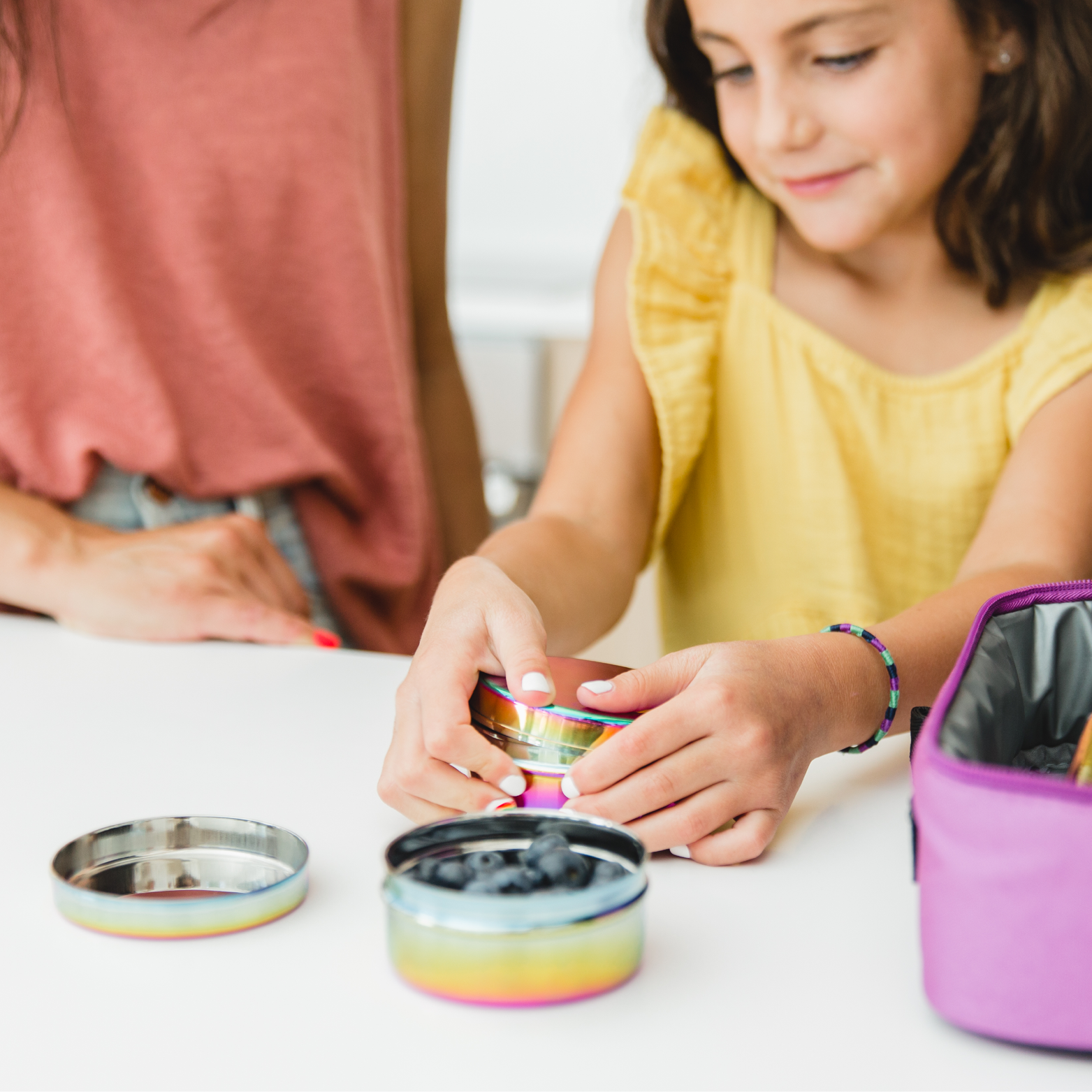 Young girl packing her lunch for the day with Ahimsa's Movable Meal Collection, The Circle Trio -  designed to nest, stack and store so you can move your meal with you—wherever you dine. 