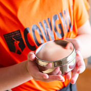 Child holding stainless steel circle container for lunches, snacks, and on-the-go