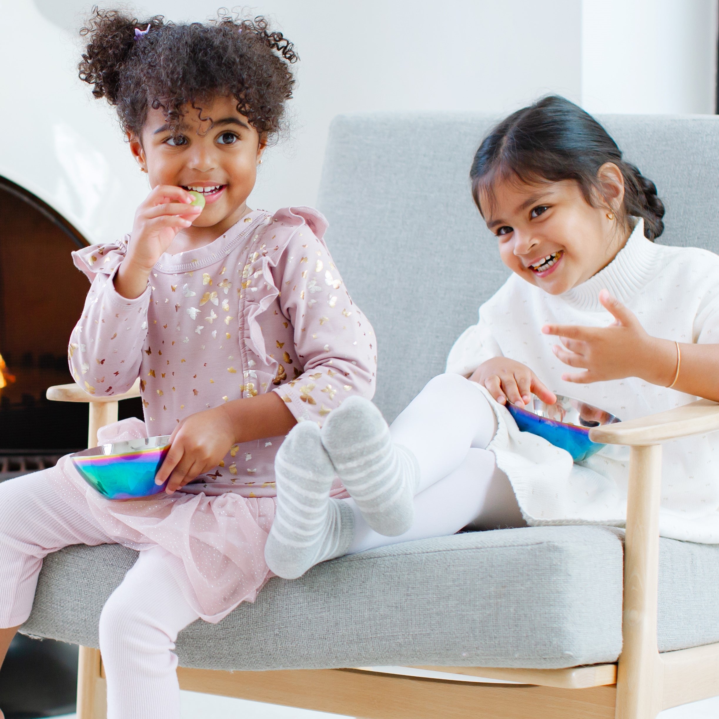 Two girls with a rainbow bowl and blue bowl by the fire - stainless steel bowls for kids