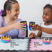 Two children with rainbow-colored cups and bowls on a table.