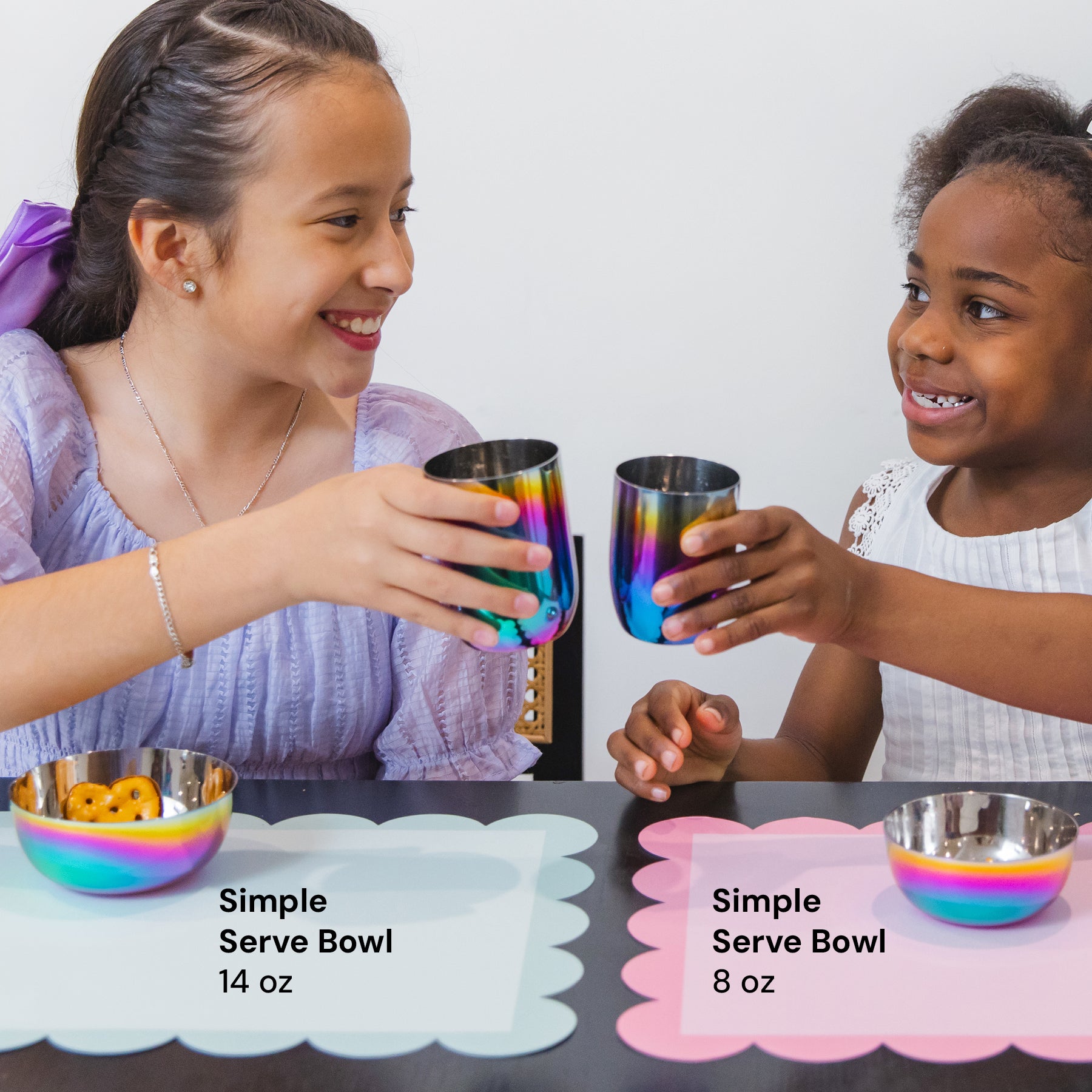 Two children with rainbow-colored cups and bowls on a table.
