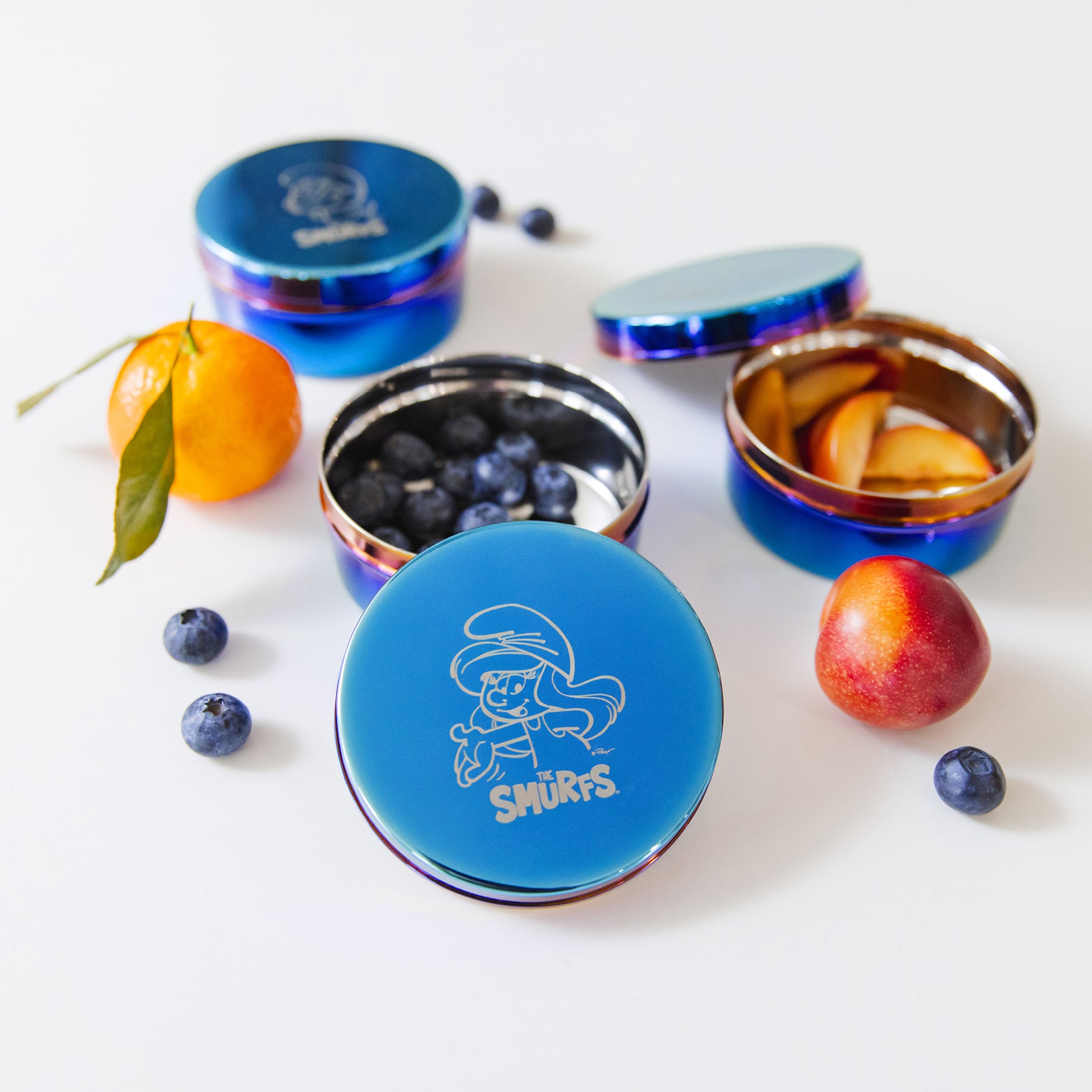 Blue container with 'Smurfs' design surrounded by fruits on a white background