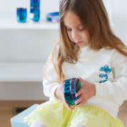 Young girl holding in Smurf sweatshirt opening a blue stainless steel food container in a home setting