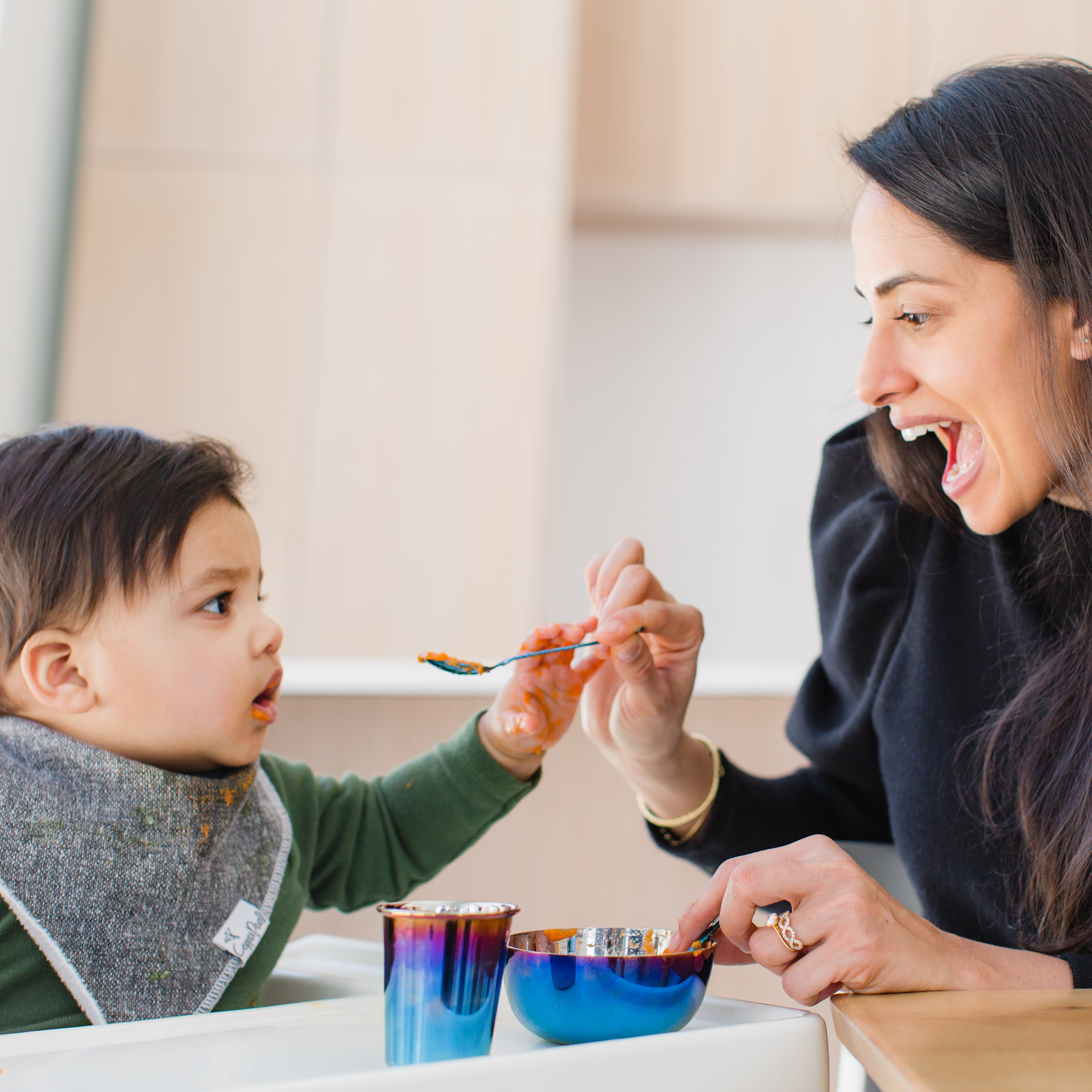 mom feeding littles with a set of stainless steel dishes for toddlers