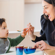mom feeding littles with a set of stainless steel dishes for toddlers