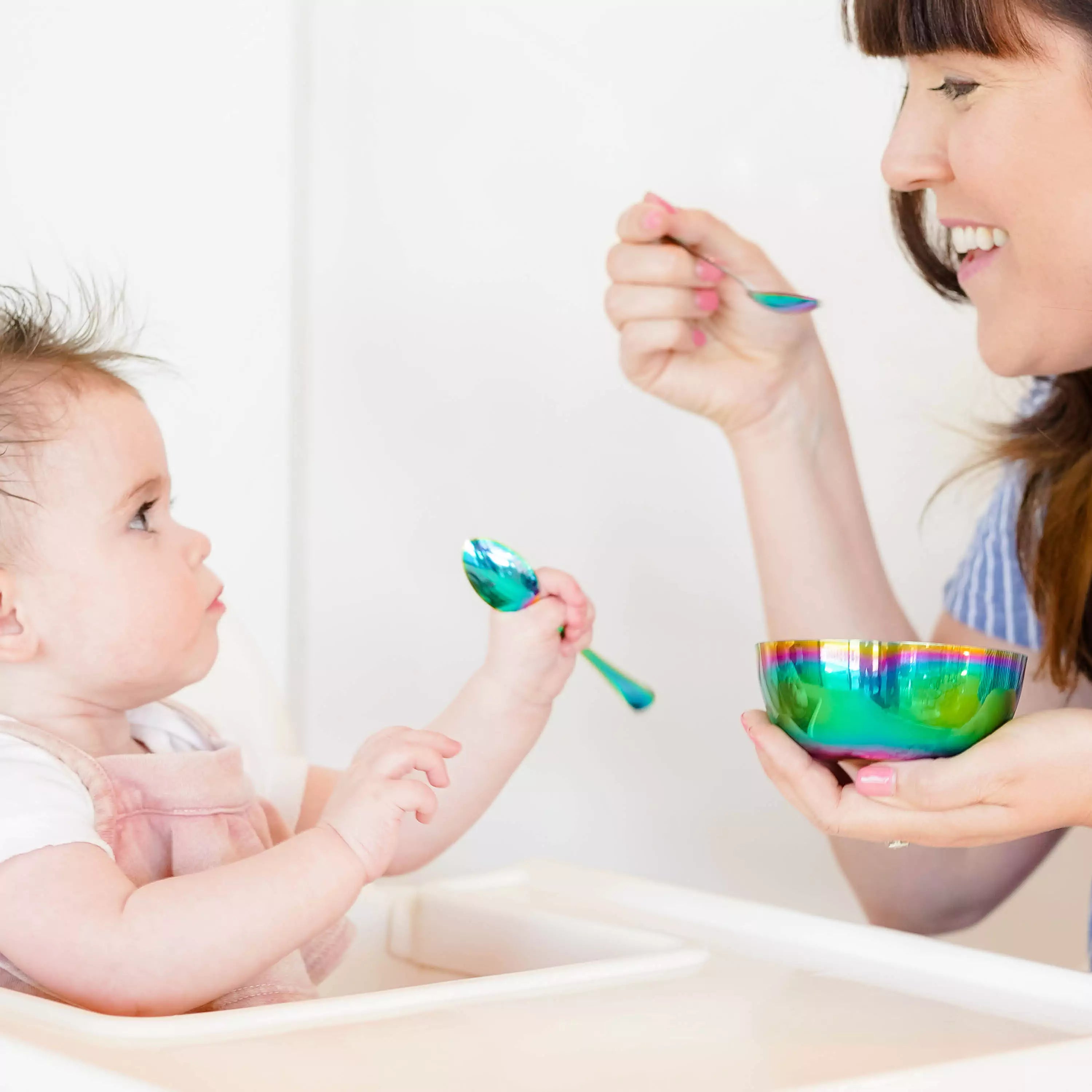 mom feeding a baby with ahimsa stainless steel baby spoons and infant holding baby spoon for self feeding