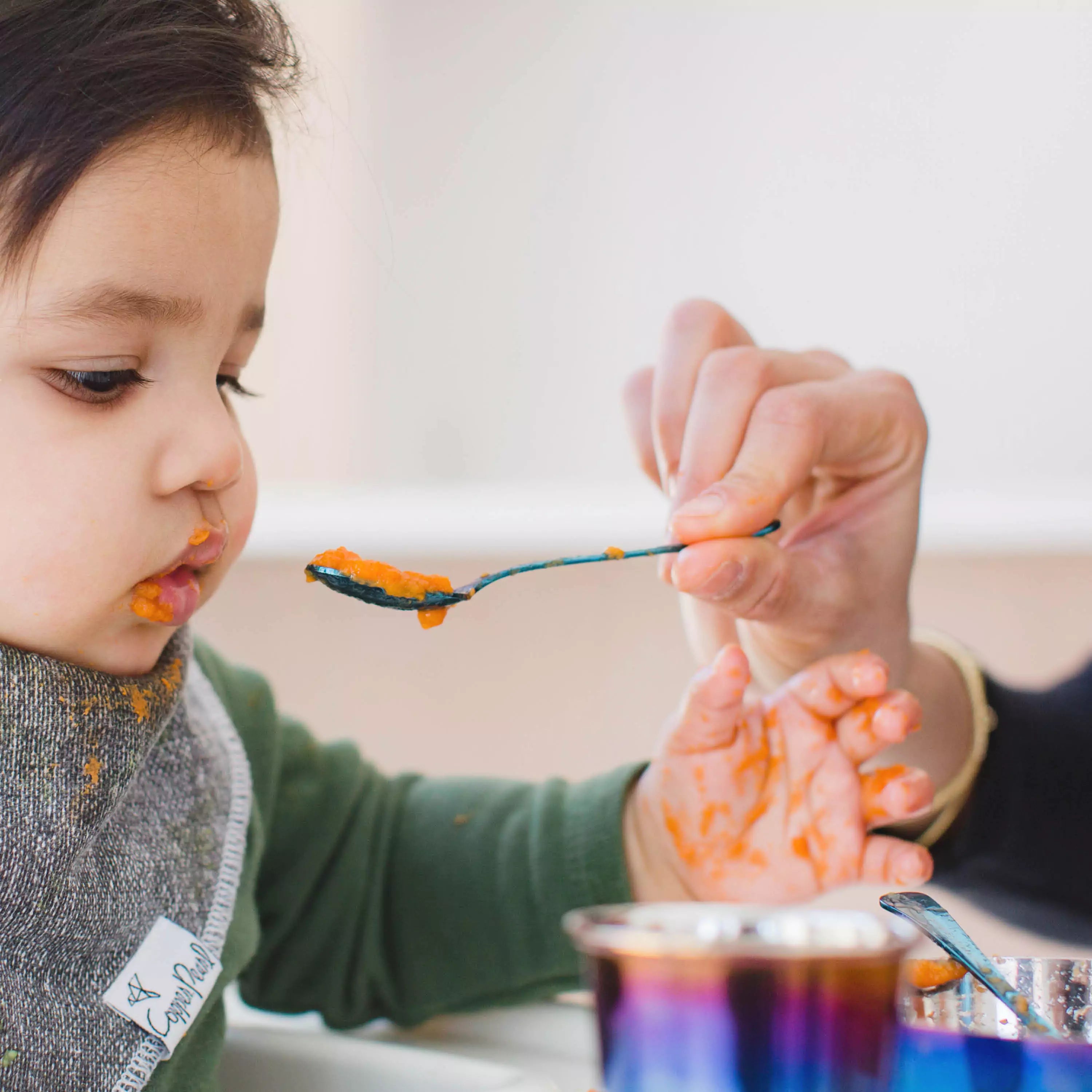 toddler eating pureed carrots from ahimsa toddler spoon in blue finish