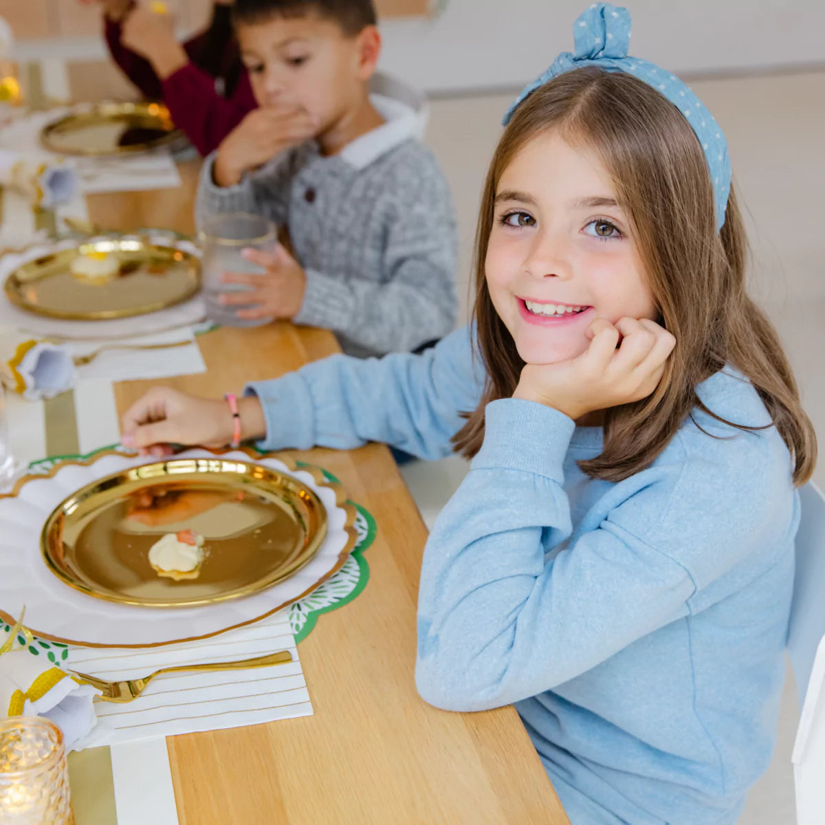 10 year old girl and 8 year old boy with gold plates and gold utensils with adorable place settings