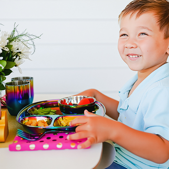 Toddler enjoying Mindful Mealtime Set with stainless steel compartment plate, 8 oz bowl, 8 oz cup, fork and spoon - safe, eco-friendly, easy to plate with a variety of healthy foods in age-appropriate portions and easy to clean - rinses easily and dishwasher safe